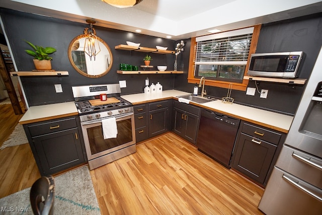 kitchen with sink, pendant lighting, stainless steel appliances, and light hardwood / wood-style floors