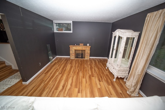 interior space with a textured ceiling, hardwood / wood-style flooring, and a stone fireplace