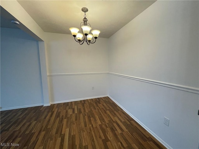 unfurnished room featuring dark hardwood / wood-style floors and an inviting chandelier