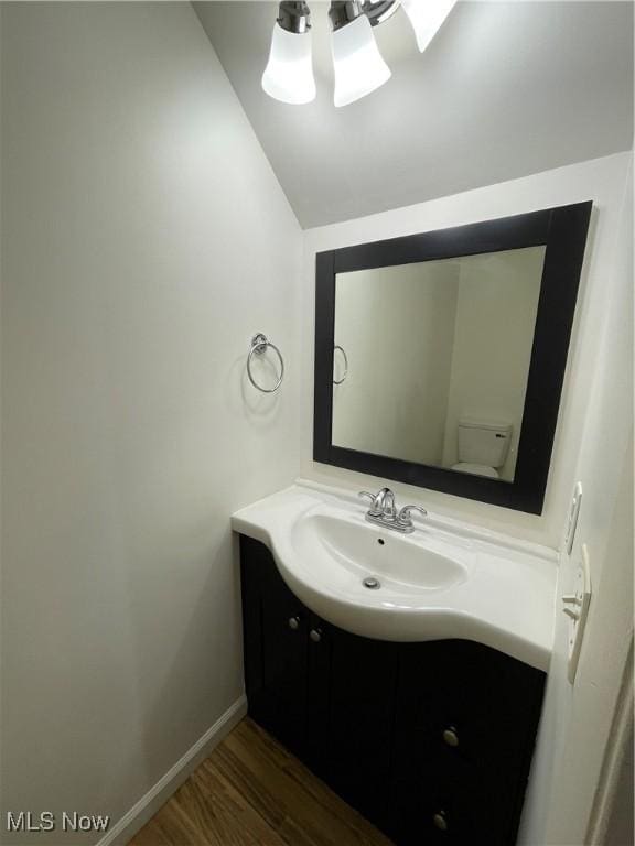 bathroom featuring wood-type flooring, vanity, and lofted ceiling