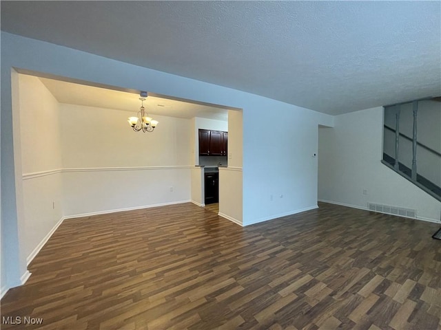 unfurnished living room featuring a textured ceiling, dark wood-type flooring, and a notable chandelier