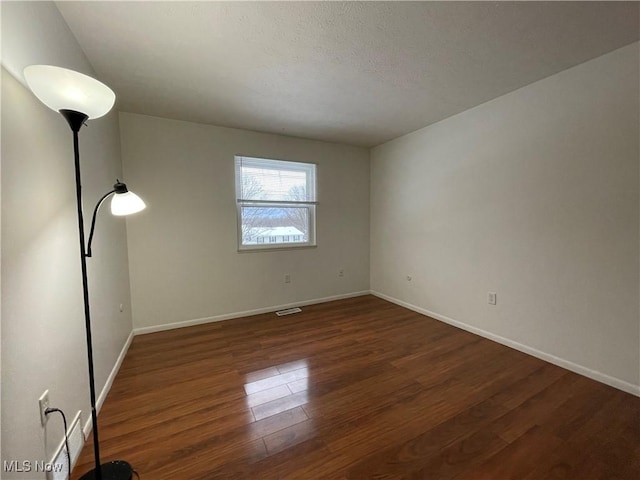 spare room featuring dark wood-type flooring