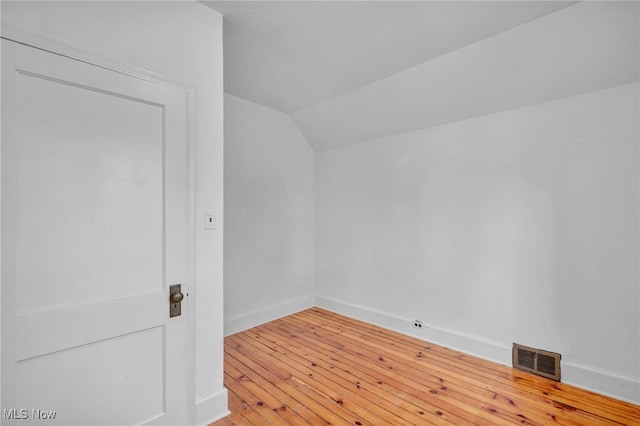 unfurnished room with hardwood / wood-style floors and lofted ceiling