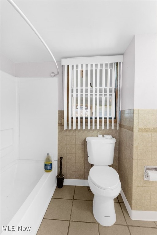 bathroom with tile patterned flooring, toilet, and tile walls