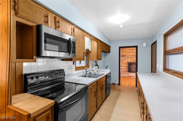 kitchen with tasteful backsplash, sink, black appliances, and light wood-type flooring