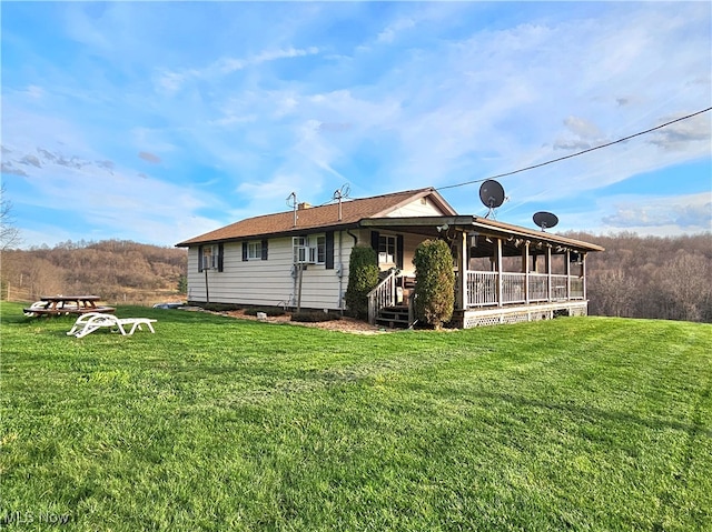 rear view of house with a lawn and a sunroom