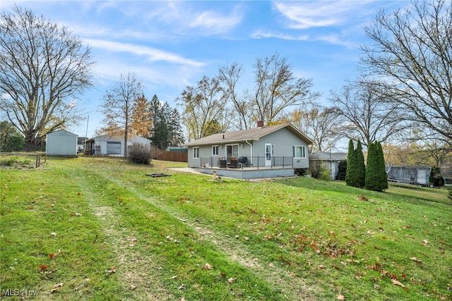 rear view of property with a lawn, a deck, and a storage unit