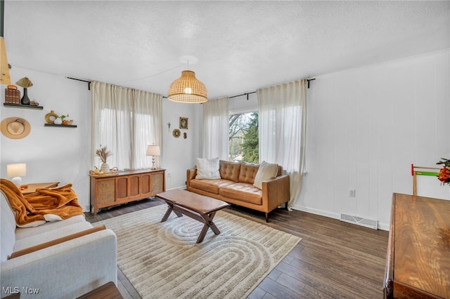 living room with a textured ceiling and dark hardwood / wood-style floors