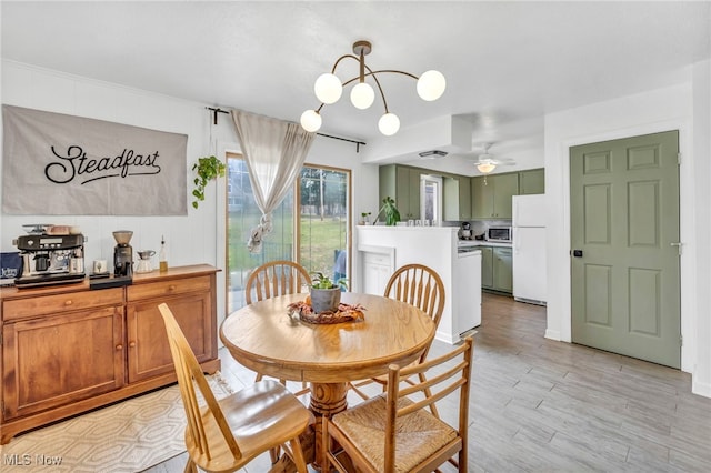 dining room featuring ceiling fan with notable chandelier and light hardwood / wood-style flooring