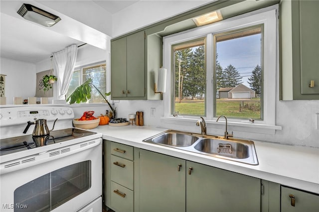 kitchen with decorative backsplash, sink, white electric range oven, and green cabinetry