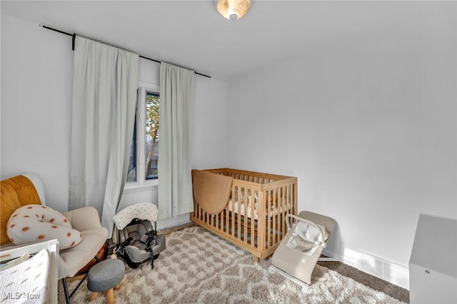 bedroom featuring light colored carpet and a nursery area