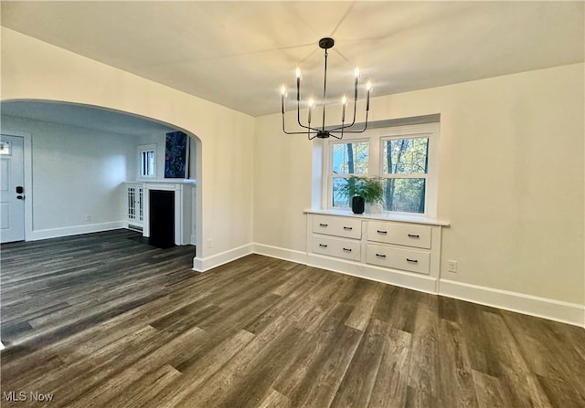 unfurnished dining area featuring a notable chandelier and dark hardwood / wood-style flooring