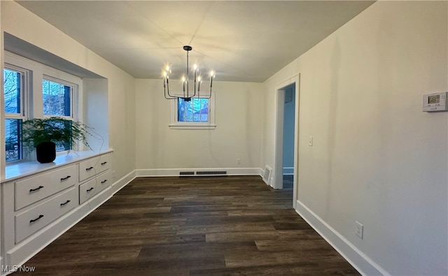 unfurnished dining area with a chandelier and dark hardwood / wood-style floors