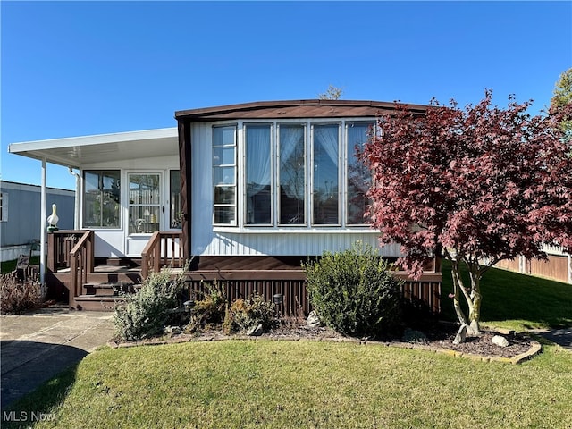 rear view of house with a lawn and a sunroom