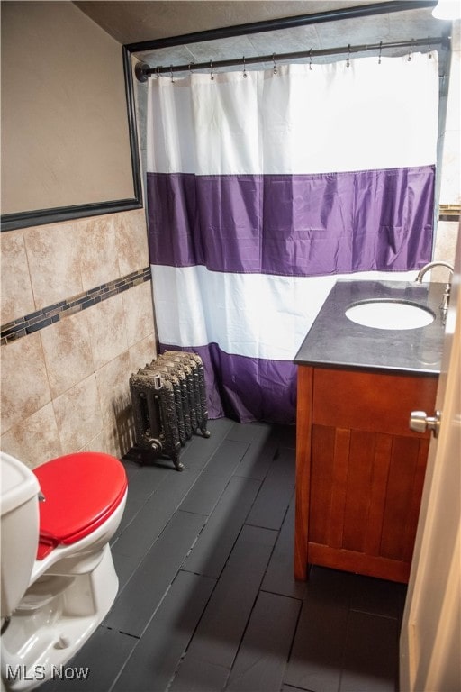 bathroom with walk in shower, vanity, toilet, and tile walls