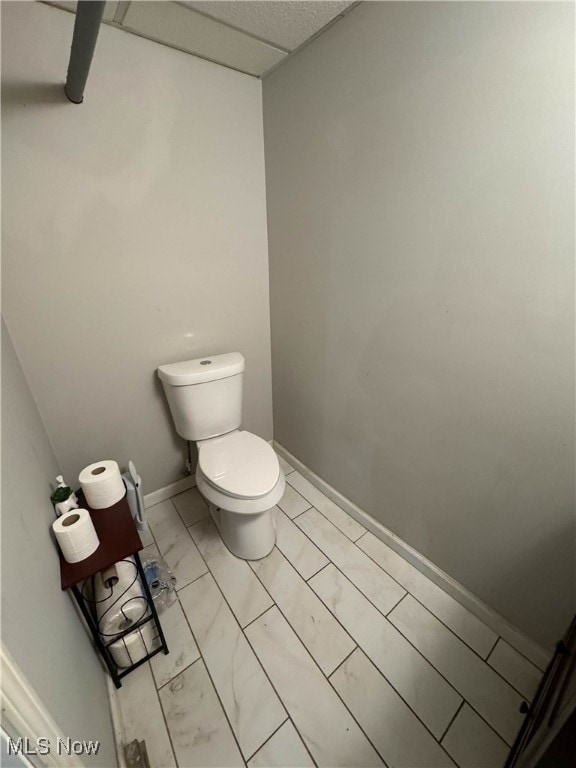 bathroom featuring a drop ceiling and toilet