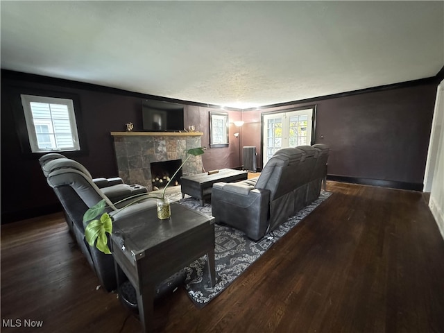 living room featuring a stone fireplace, dark hardwood / wood-style flooring, and ornamental molding