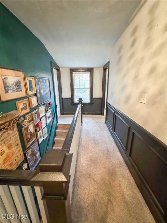 corridor with light carpet and vaulted ceiling