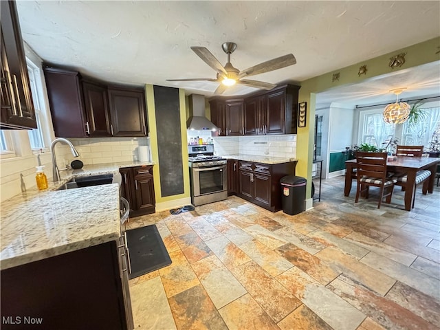 kitchen with decorative backsplash, stainless steel range with gas cooktop, sink, and wall chimney range hood