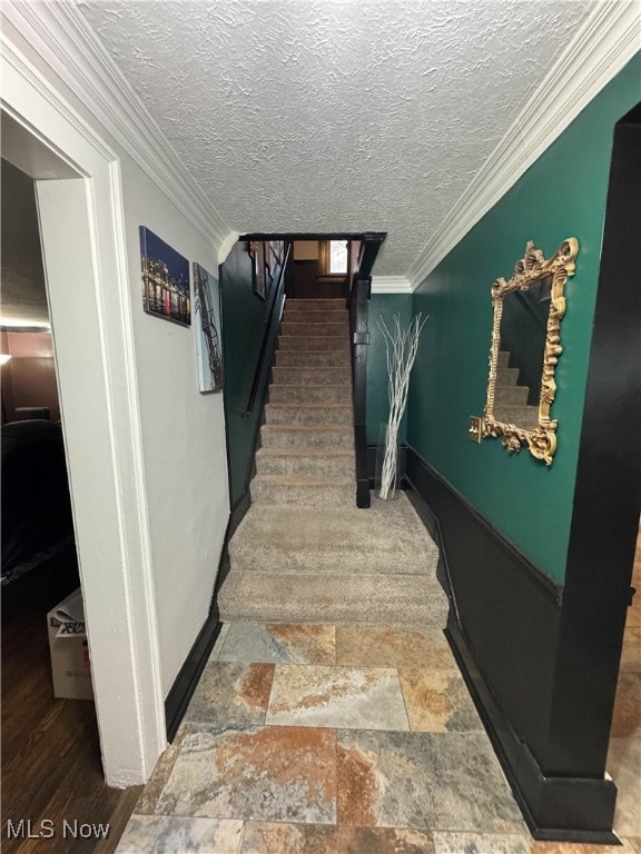 staircase with a textured ceiling and ornamental molding