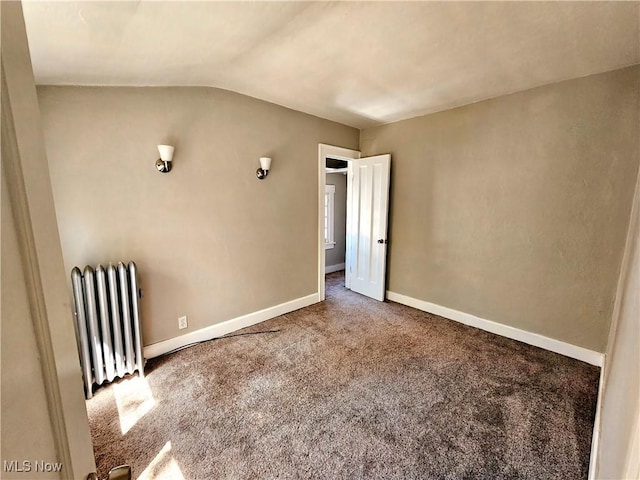 carpeted empty room with baseboards, vaulted ceiling, and radiator