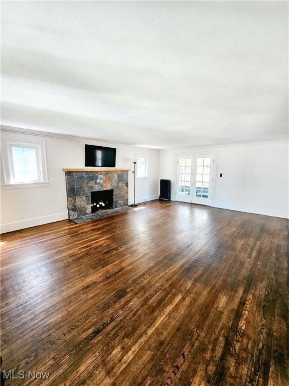 unfurnished living room featuring baseboards, a fireplace with flush hearth, and wood finished floors