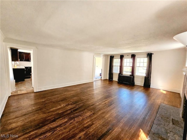 unfurnished living room with baseboards, a fireplace with flush hearth, dark wood finished floors, and ornamental molding