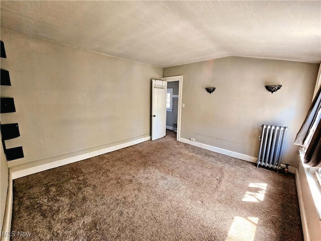 carpeted empty room with baseboards, lofted ceiling, and radiator