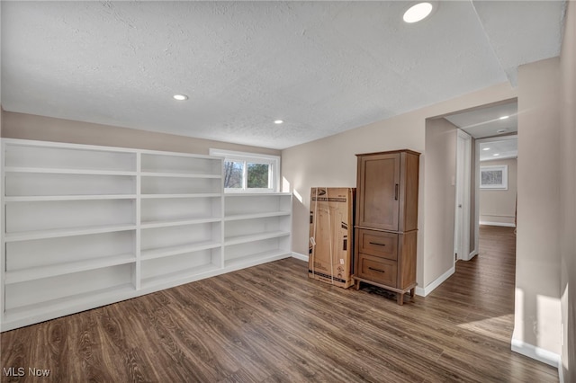 spare room featuring dark hardwood / wood-style floors, a textured ceiling, and built in shelves