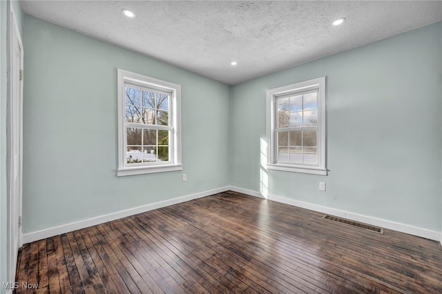 empty room featuring dark hardwood / wood-style flooring and a textured ceiling