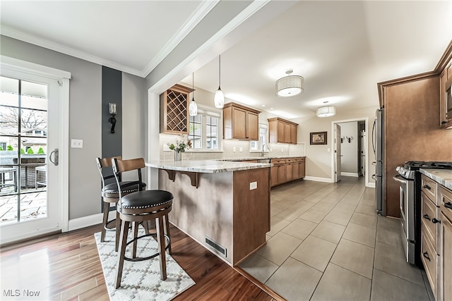 kitchen with decorative light fixtures, stainless steel appliances, a wealth of natural light, and light hardwood / wood-style floors