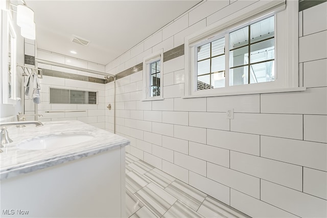 bathroom featuring a shower, vanity, and tile walls