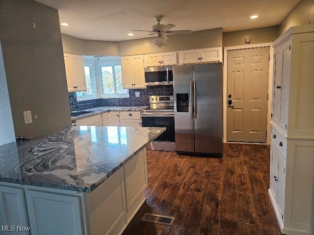 kitchen featuring stone counters, white cabinetry, dark wood-type flooring, tasteful backsplash, and appliances with stainless steel finishes