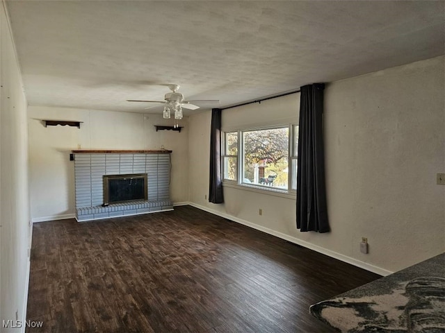 unfurnished living room featuring ceiling fan, dark hardwood / wood-style flooring, and a brick fireplace