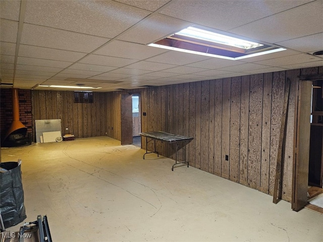 basement featuring a paneled ceiling and wood walls