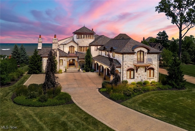 view of front of property featuring a garage, a balcony, and a yard