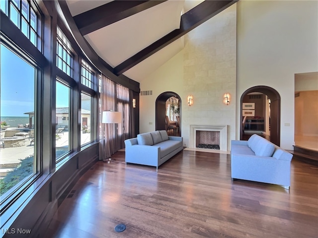 unfurnished living room with beam ceiling, a fireplace, high vaulted ceiling, and dark wood-type flooring