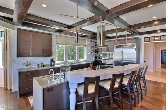 kitchen with island range hood, sink, built in appliances, a center island with sink, and dark hardwood / wood-style floors