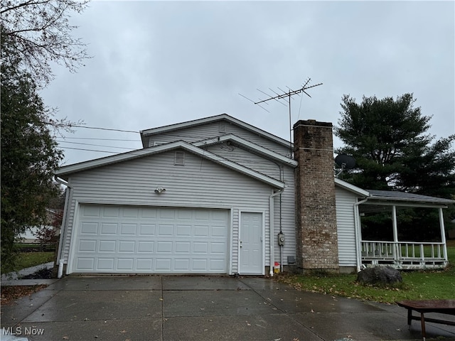 view of front of home with concrete driveway, a chimney, and an attached garage