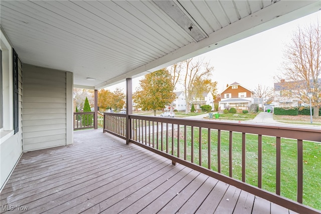 wooden deck with a lawn and covered porch