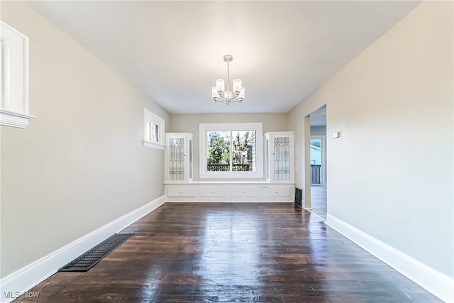 unfurnished dining area with dark hardwood / wood-style floors and a notable chandelier