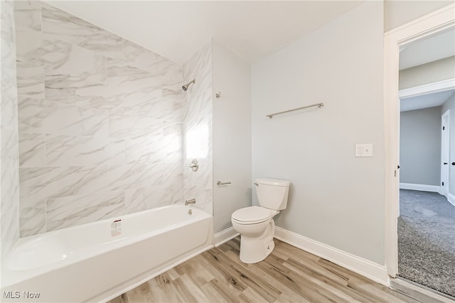 bathroom with tiled shower / bath combo, toilet, and wood-type flooring