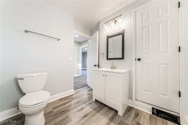 bathroom featuring vanity, wood-type flooring, and toilet