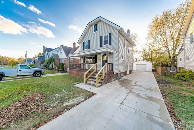 view of front of house featuring covered porch, a garage, an outbuilding, and a front lawn