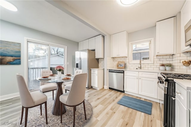 kitchen with light wood-type flooring, stainless steel appliances, and white cabinetry