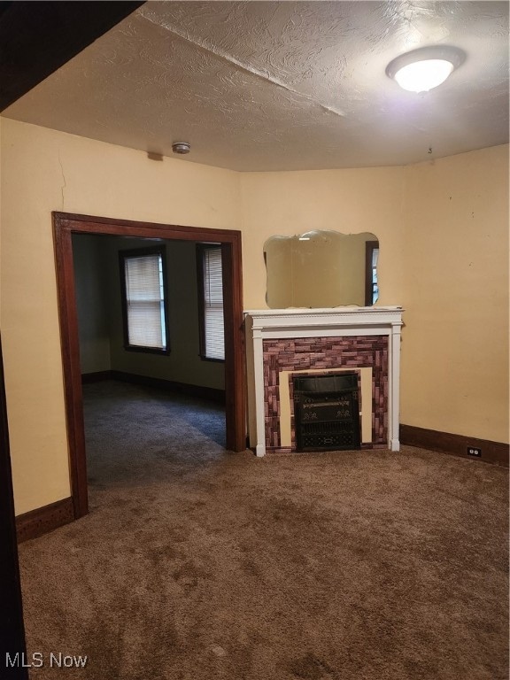 unfurnished living room featuring a textured ceiling and dark carpet