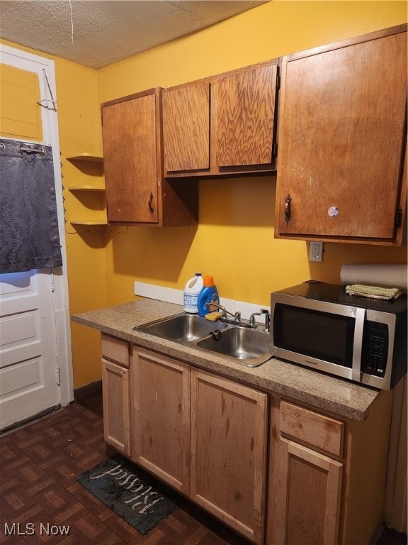 kitchen with dark parquet flooring, sink, and a textured ceiling