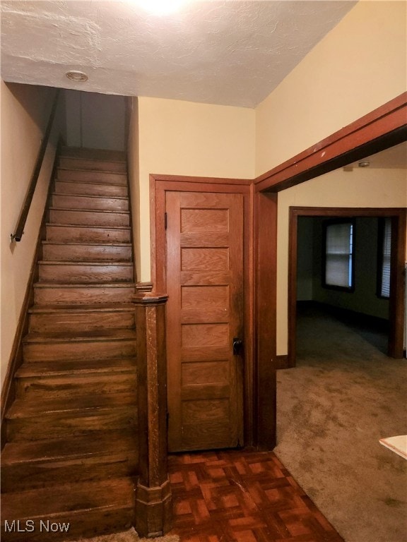 stairs with a textured ceiling and carpet floors