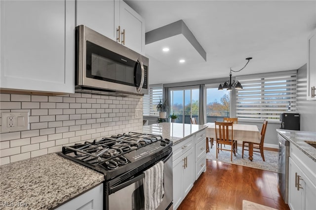 kitchen with light stone countertops, dark hardwood / wood-style flooring, white cabinets, and appliances with stainless steel finishes