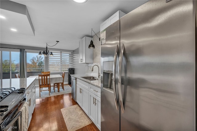 kitchen featuring white cabinets, decorative light fixtures, stainless steel appliances, and sink